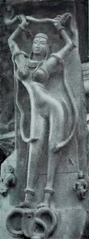 A slender woman carved on a pillar bracket, with both arms raised over her head and snake coils at her feet.