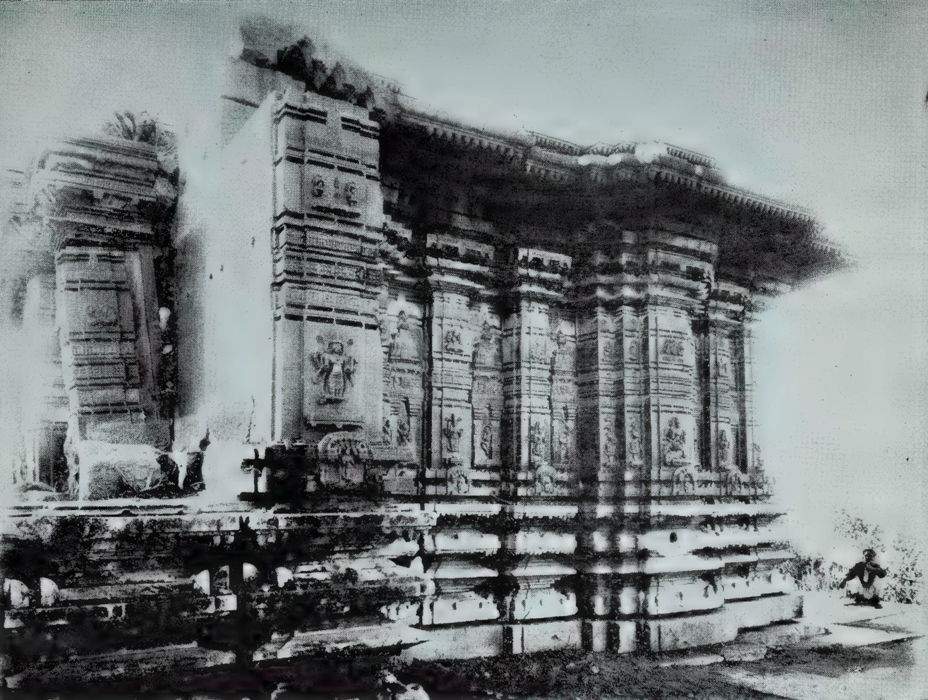 An old black-and-white photograph of a temple sanctum seen from one corner. Its walls are covered with carved pilasters and niches, under a deep cornice, on a moulded base.