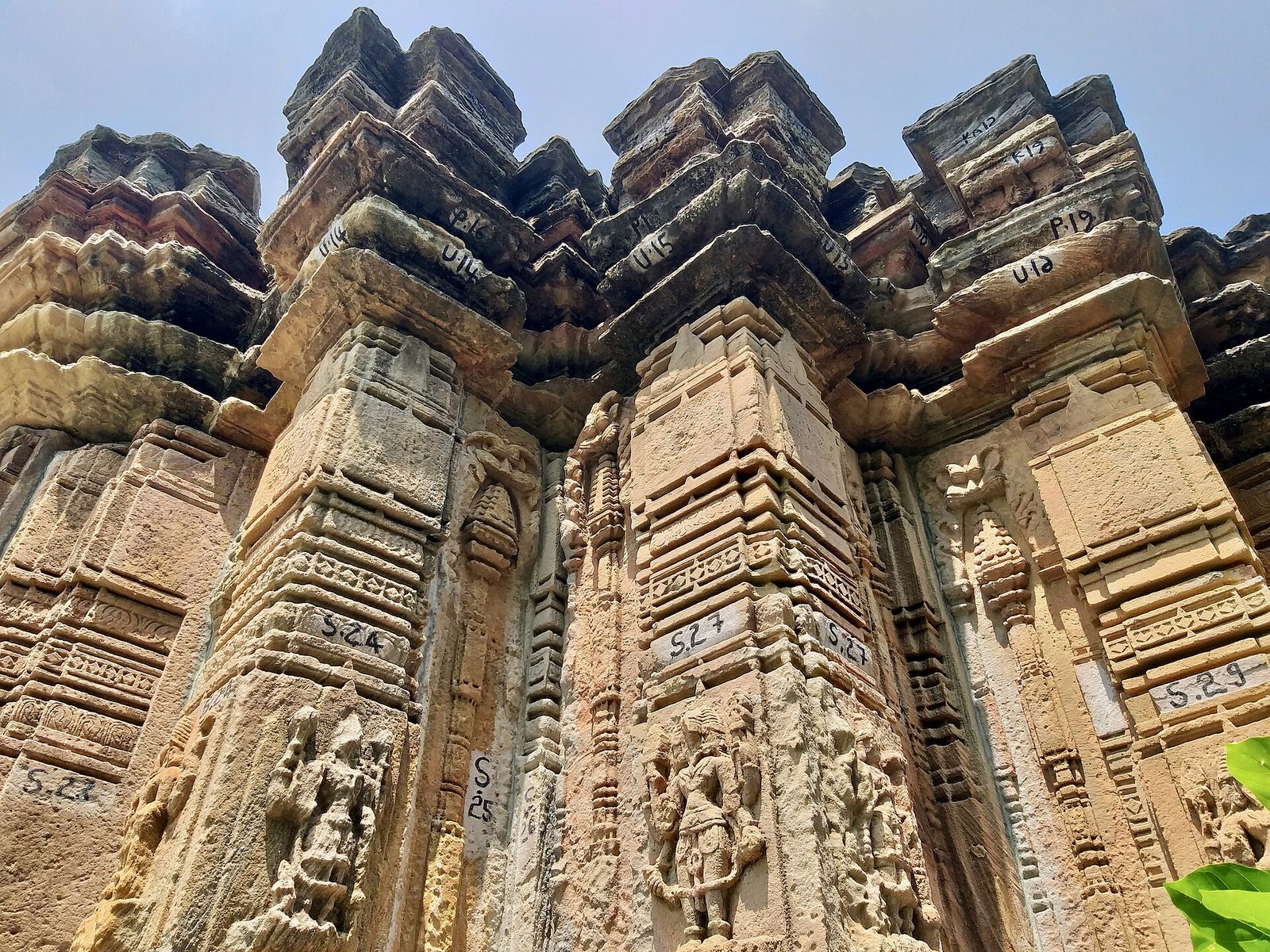 Close view of angled stone wall projections, each with small carved sculptures in niches, rising in stepped layers.