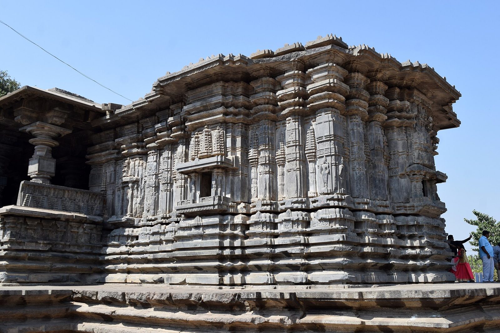Close view of one shrine block of the Thousand Pillar Temple against a blue sky, its wall broken into many vertical pilasters and niches above stacked horizontal mouldings